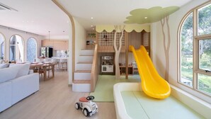 A modern interior with a play area, a slide, a dining area, and a kitchen. - Winvilla Pattaya - Private Pool Villa 5 Bedrooms (Bang Lamung)