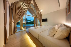 A bedroom with a large bed, a TV on the wall, and a view of a pool through the window. - Winvilla Pattaya - Private Pool Villa 5 Bedrooms (Bang Lamung)