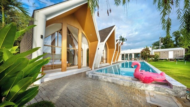A modern house with a swimming pool, a pink flamingo float, and a well-maintained lawn. - Winvilla Pattaya - Private Pool Villa 5 Bedrooms (Bang Lamung)