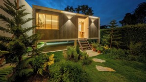 A modern house with a wooden exterior, a visible staircase, and a small garden with various plants. - Winvilla Pattaya - Private Pool Villa 5 Bedrooms (Bang Lamung)