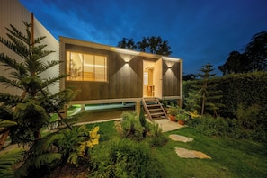 A modern house with a wooden exterior, a visible staircase, and a small garden with various plants. - Winvilla Pattaya (Bang Lamung)