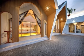 A modern hotel with a spacious courtyard, large arched windows, and a well-lit interior. - Winvilla Pattaya (Bang Lamung)