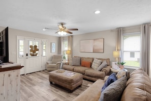 A living room with a ceiling fan, a sofa set, a coffee table, and a television.