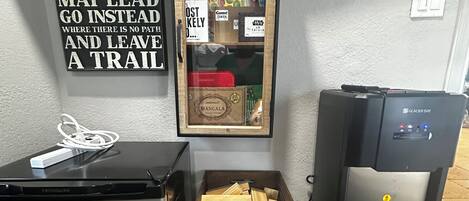 A kitchenette with a refrigerator, a drawer with wooden planks, a water dispenser, and a wall with a motivational quote.