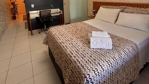 Quarto de hotel com cama, escrivaninha e cadeira.