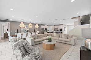 Ein modernes Wohnzimmer mit einem Ecksofa, einem runden Couchtisch und Pendelleuchten.