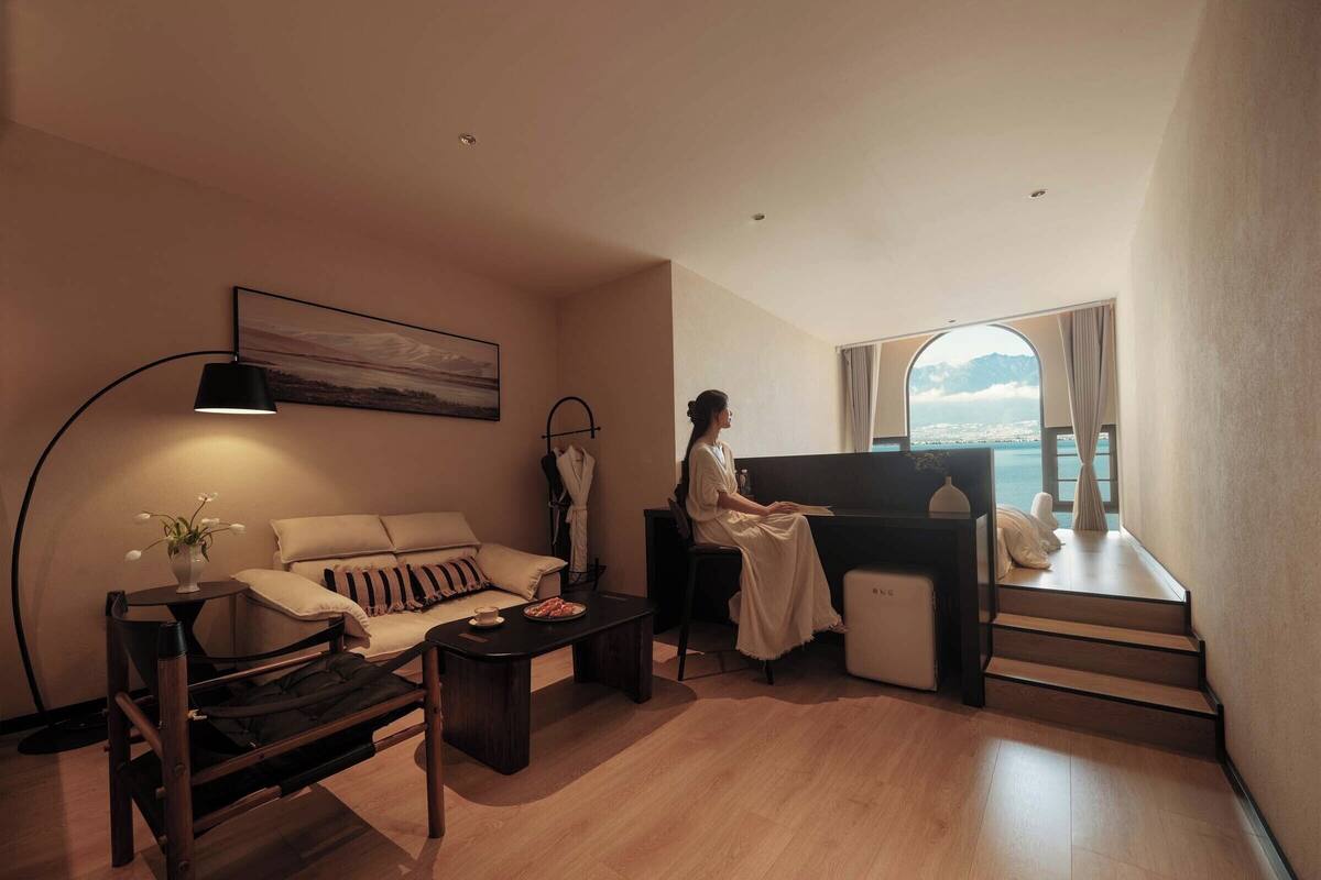 A modern living room with a sofa, a coffee table, a lamp, and a view of the sea.
