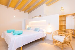 Ein Schlafzimmer mit einem Bett, einem Sessel, einem Nachttisch, einem Wandregal und einer Pendelleuchte.