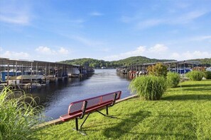 Ein Uferweg mit einer Bank, einer Schleusenanlage und einer Brücke.