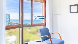 Una habitación con un ventanal grande, una silla azul y un logotipo en el vidrio.