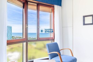 Ein Zimmer mit einem großen Fenster, einem blauen Stuhl und einem Logo am Fenster.