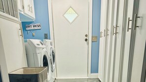A laundry area with a washing machine, a drying rack, and a sign that reads 'LOST SOCKS SEEKING SOUL MATERIALS'.
