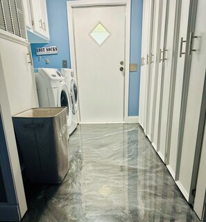 A laundry area with a washing machine, a drying rack, and a sign that reads 'LOST SOCKS SEEKING SOUL MATERIALS'.
