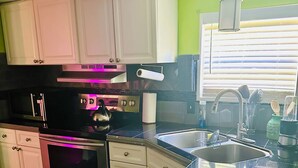 A modern kitchen with stainless steel appliances, a black countertop, and white cabinetry.