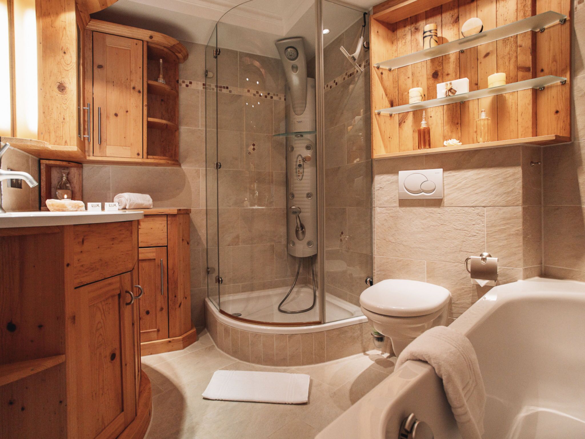 Une salle de bain avec une douche à parois de verre, une baignoire, des meubles en bois et une étagère contenant des articles de toilette.