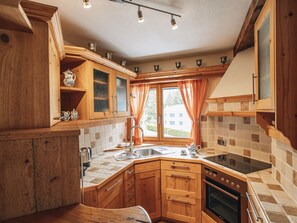 Eine Küche mit Holzausstattung, Spüle, Herd und einem Fenster mit Vorhängen.