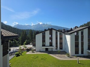Ein modernes Gebäude mit Flachdach, großen Fenstern und Blick auf Berge.