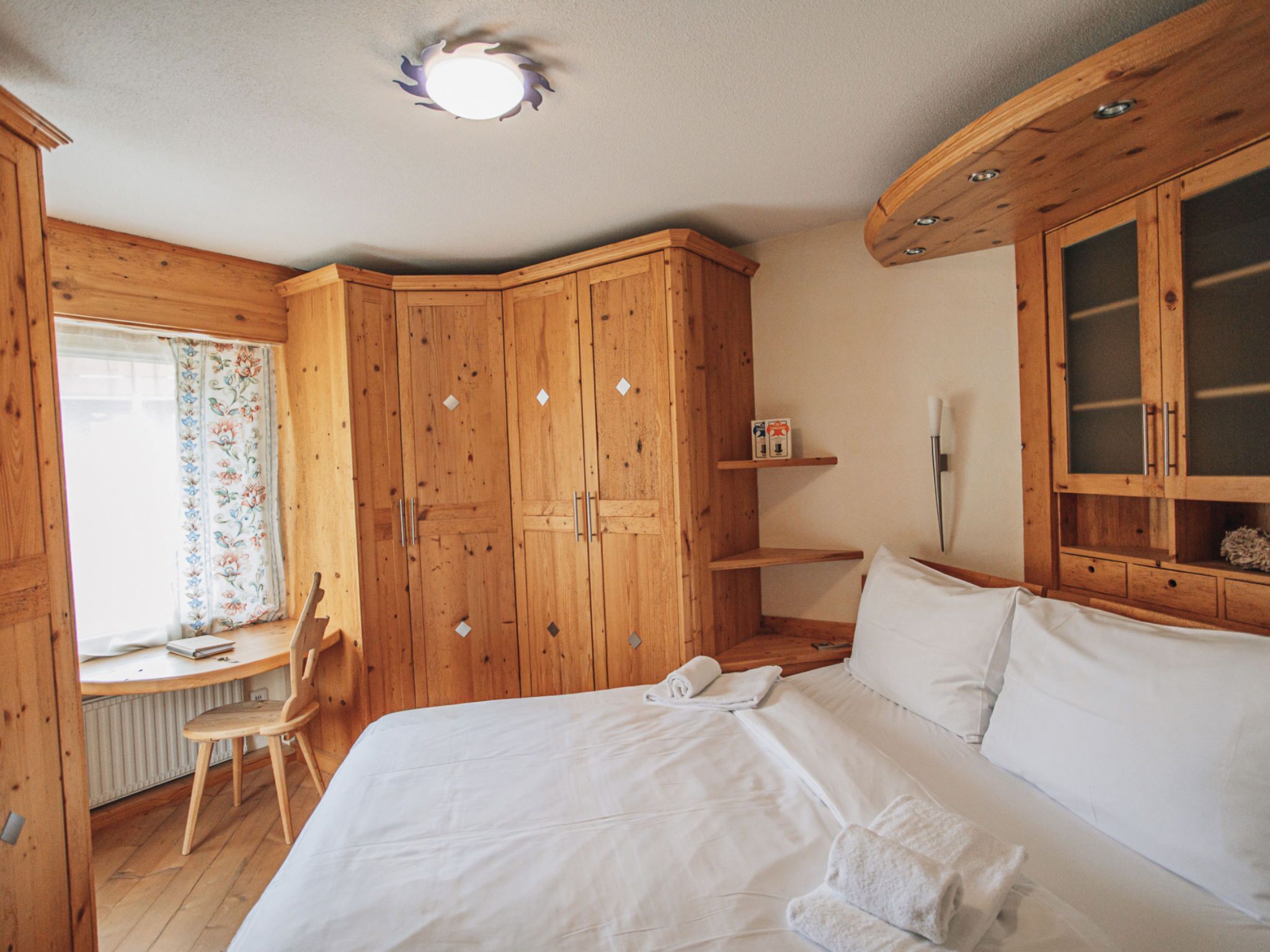 Une chambre à coucher avec des meubles en bois, un lit, un bureau et une chaise.