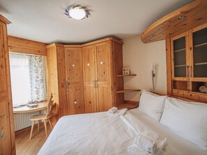 Ein Schlafzimmer mit Holzmöbeln, einem Bett, einem Schreibtisch und einem Stuhl.