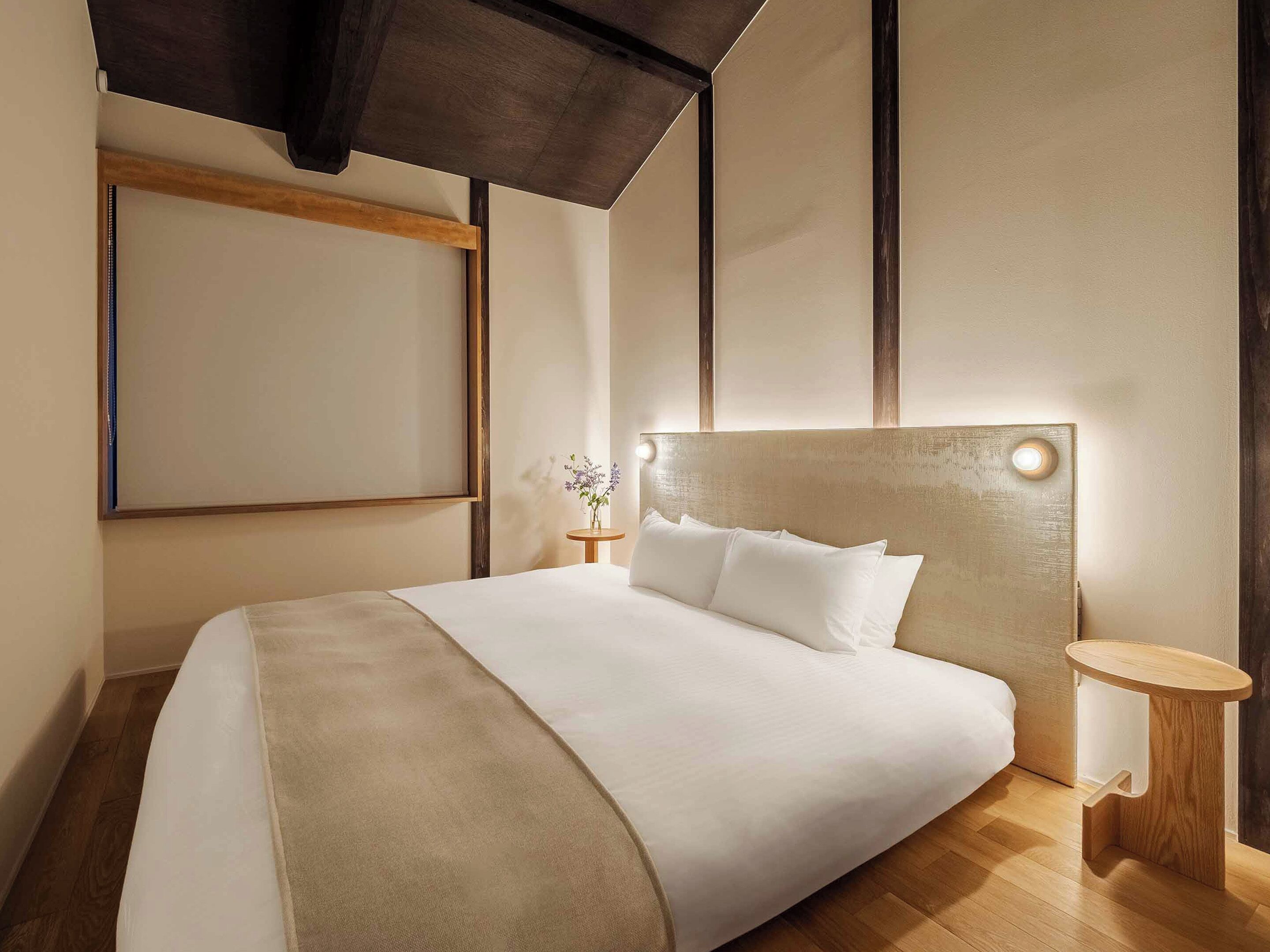 A modern hotel room with a large bed, a bedside table, and a wall-mounted TV.