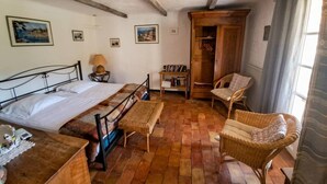 Ein Zimmer mit einem Bett, einem Holzschrank, Korbstühlen und einem kleinen Tisch.