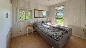 A bedroom with a bed, a nightstand, a mirror, and two windows. - Awesome home in Rødby with WiFi (Rødby)