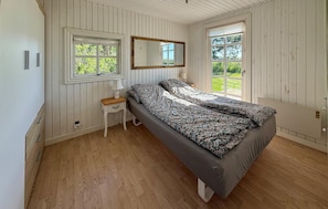 A bedroom with a bed, a nightstand, a mirror, and two windows. - Beautiful home in Rødby with WiFi (Rødby)