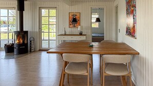A dining area with a wooden table and chairs, a fireplace, and a view through a glass door. - Awesome home in Rødby with WiFi (Rødby)