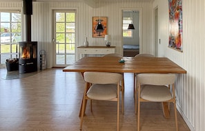 A dining area with a wooden table and chairs, a fireplace, and a view through a glass door. - Beautiful home in Rødby with WiFi (Rødby)