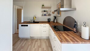 A compact kitchen with white cabinetry, a wooden countertop, a dishwasher, and a coffee maker. - Awesome home in Rødby with WiFi (Rødby)