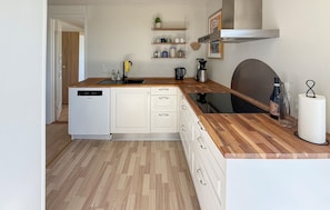 A compact kitchen with white cabinetry, a wooden countertop, a dishwasher, and a coffee maker. - Beautiful home in Rødby with WiFi (Rødby)