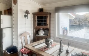 A dining area with a table, chairs, a cabinet with glass doors, a view of a body of water, and a window.