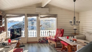 Ein gemütliches Zimmer mit Fernseher, Esstisch, Sofa und Meerblick.