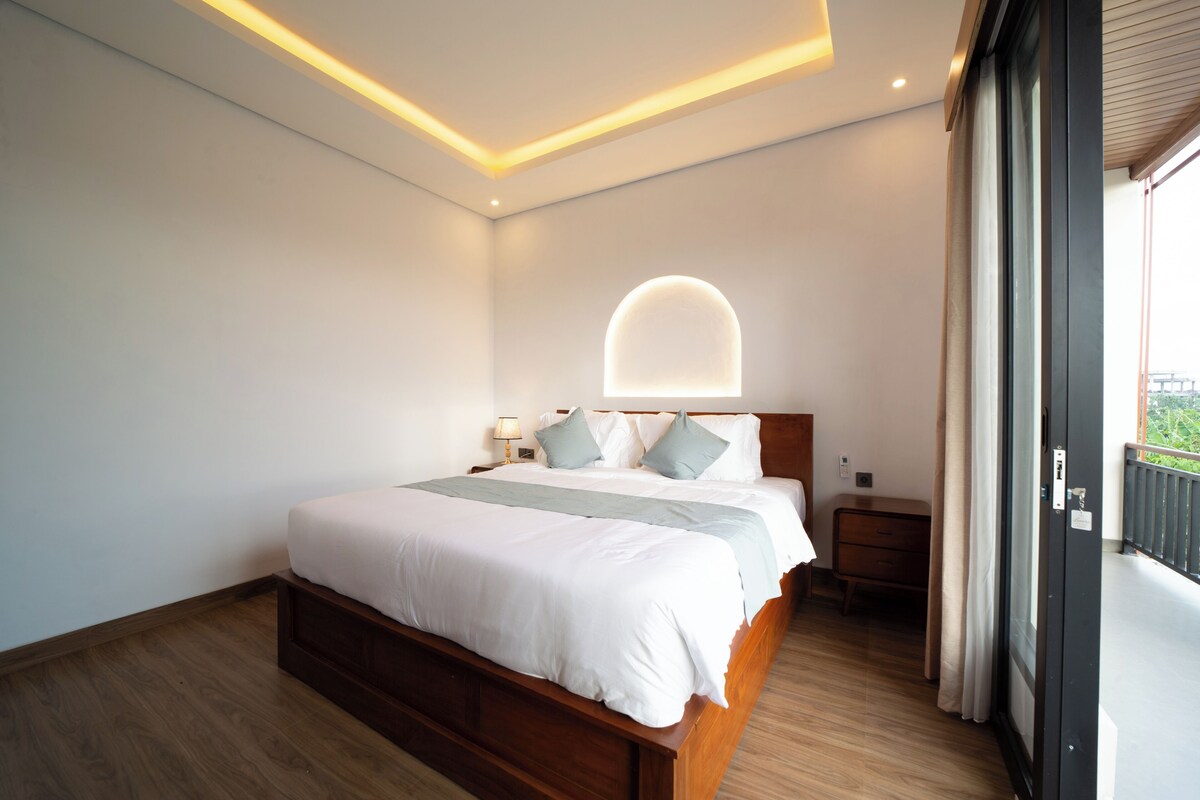Un dormitorio moderno con una cama de madera, una mesita de noche, una lámpara y un balcón con vistas.