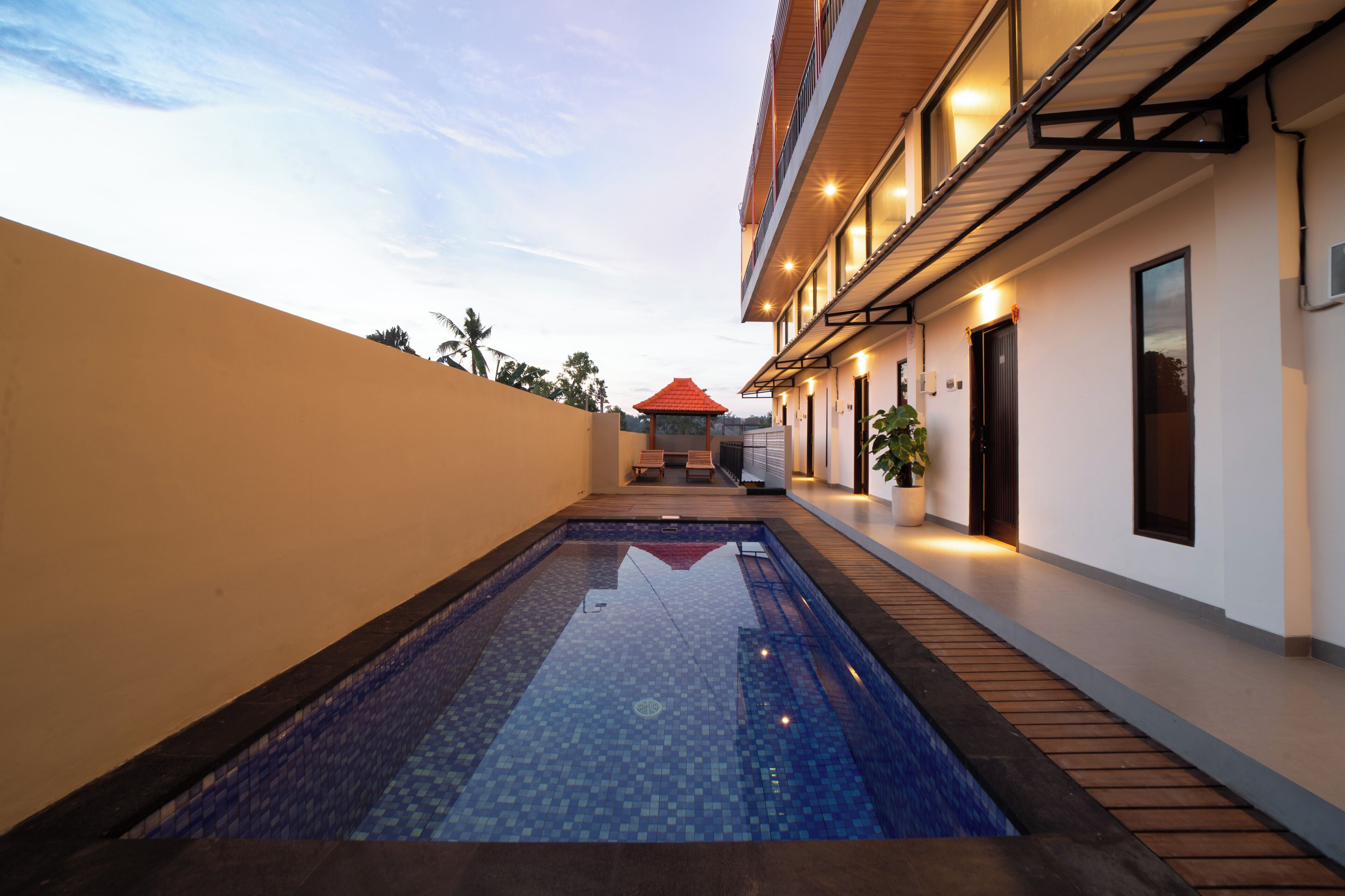 A modern building with a swimming pool, a covered seating area, and a potted plant.