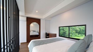 Een moderne slaapkamer met een groot bed, een bureau en een raam met uitzicht op een bos.