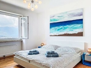 A bedroom with a bed, a window, a painting, and a nightstand. - Apt.Woka by Interhome (Aldesago)