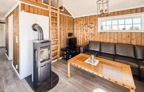 A cozy living area with a fireplace, a sofa, a TV, and a wooden table.