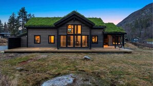 A modern log cabin with a green roof, large windows, and a deck. - Awesome home in Tjørhom with sauna (Tjørhom)