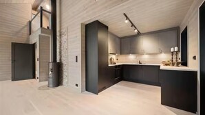 A modern kitchen with dark cabinetry, a central island, and a light-colored floor. - Awesome home in Tjørhom with sauna (Tjørhom)