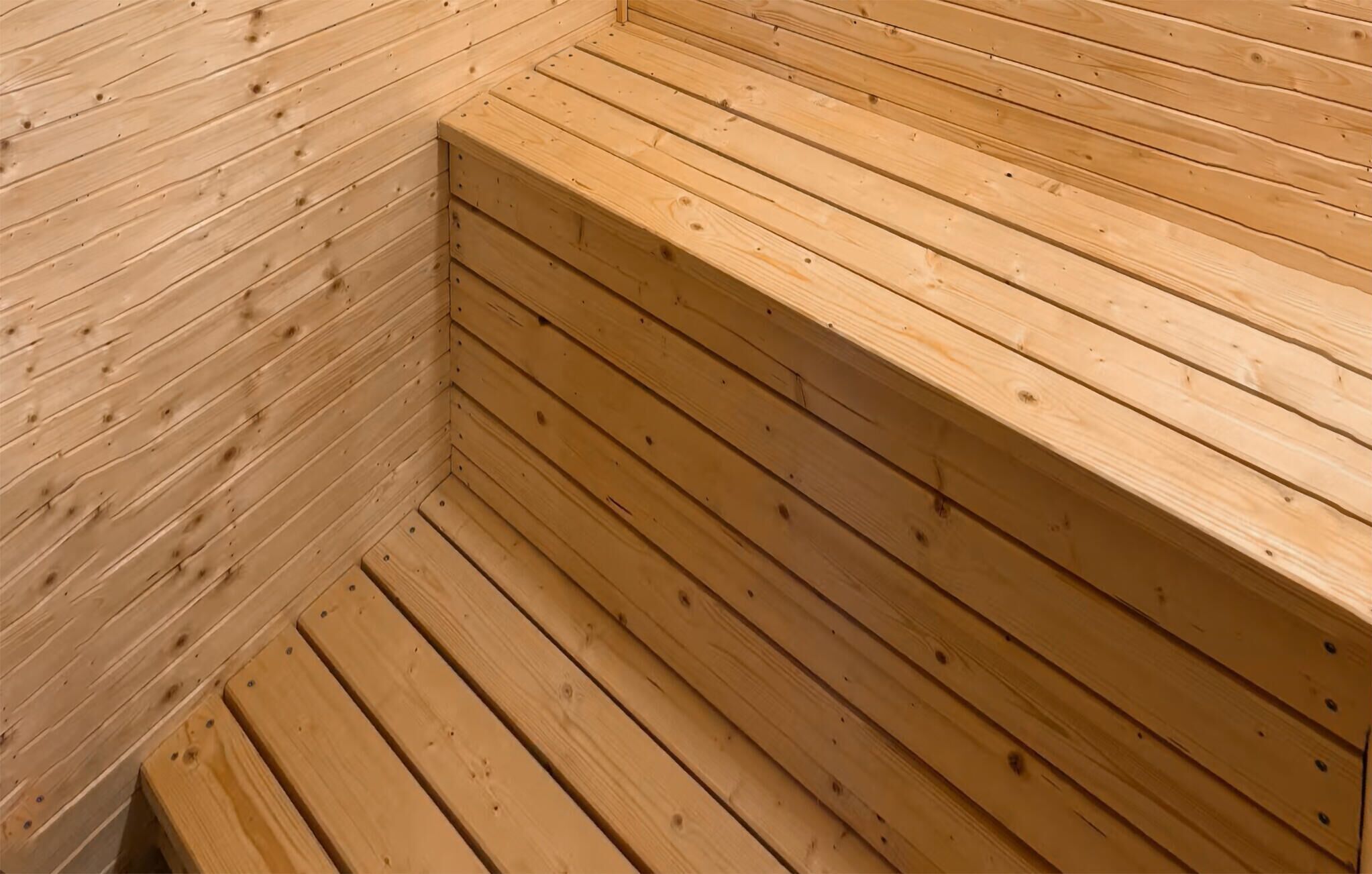 Una sauna de madera con bancos y suelo inclinado.