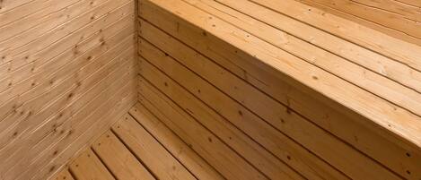 Una sauna de madera con bancos y suelo inclinado.