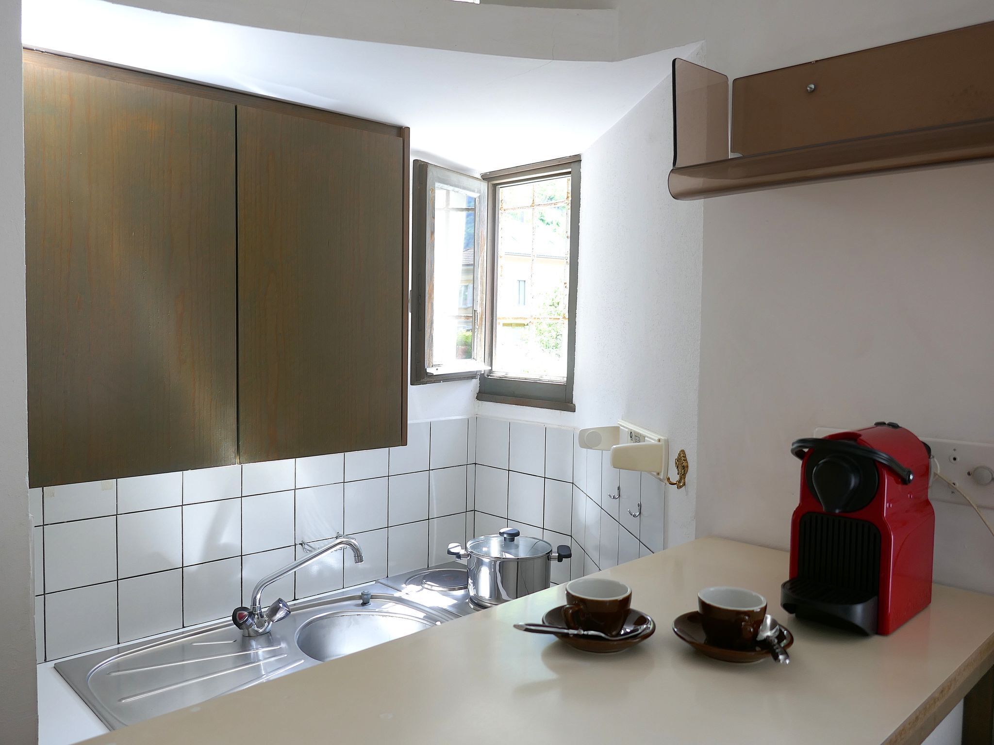 A kitchen with a sink, a window, cabinets, and a coffee maker.