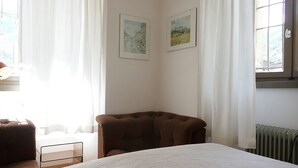 Une chambre à coucher avec un lit, une chaise, un radiateur et deux tableaux encadrés accrochés au mur.