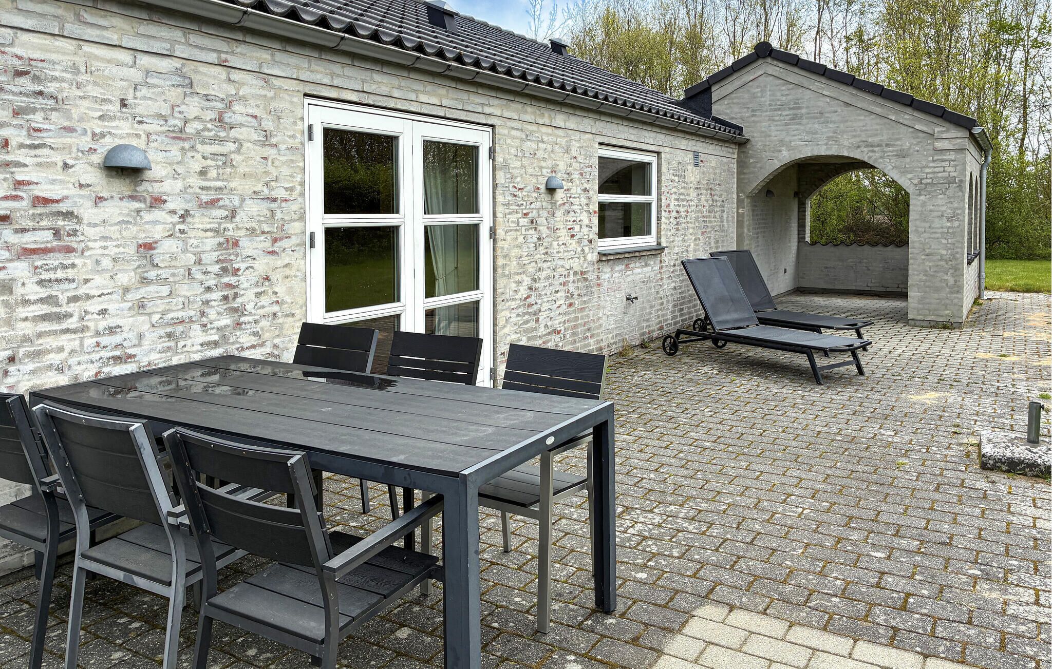 A patio with a table and chairs, a covered seating area, and a stone wall.