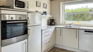 Une cuisine équipée d’un four Bosch, d’un four à micro-ondes, d’un réfrigérateur, d’une machine à café et d’un lave-vaisselle.