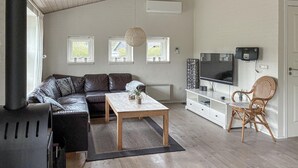 Un salon avec un canapé, une table basse, un téléviseur et un fauteuil en osier.