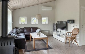 Ein Wohnzimmer mit einer Couch, einem Couchtisch, einem Fernseher und einem Korbsessel.
