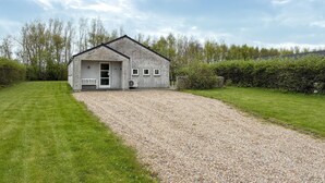 Un bâtiment en pierre d’un seul étage, avec une allée en gravier, un banc à l’extérieur et une petite fenêtre.