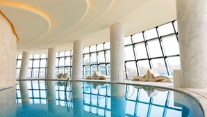 An indoor swimming pool with a clear view of the cityscape through large windows. - TAI LAKE DREAMLOHAS VILLA RESORT (Suzhou)